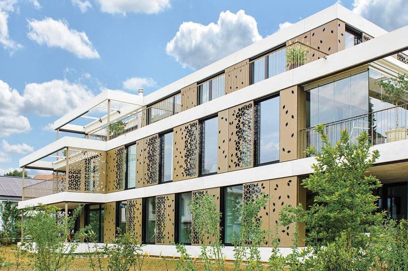 Façade d'immeuble équipée d'écrans perforés qui protègent les baies du soleil (Bellmund, Suisse)