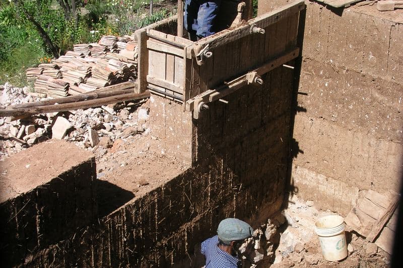 Construction d'un mur en pisé (terre crue banchée) au Pérou